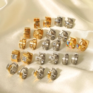 Collection of gold and silver huggie earrings with zircon and enamel on cream silk