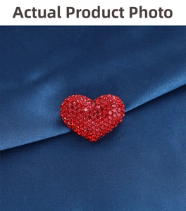 Close-up of red heart brooch with pavé rhinestones on elegant dark blue satin