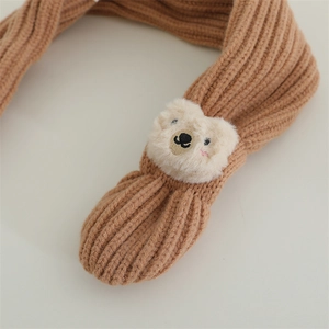 Close-up of caramel knitted baby scarf with a cute plush bear detail and soft texture