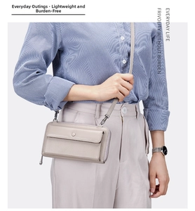 Close-up of light gray pebbled leather crossbody phone bag with metal clasps and strap