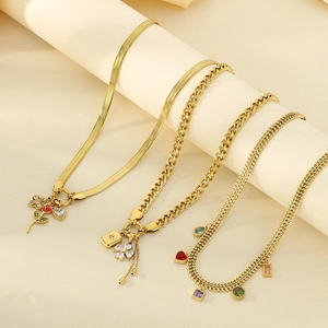 Detailed close-up of gold necklaces with red rose charms and colorful gemstones