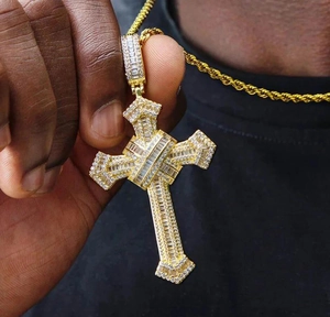 Close-up of golden hip hop cross pendant with clear zircons and twist chain necklace