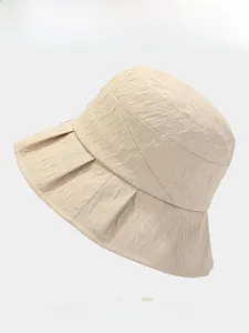 Detail showing the wavy pleated texture and wide brim of this beige cotton sun bucket hat