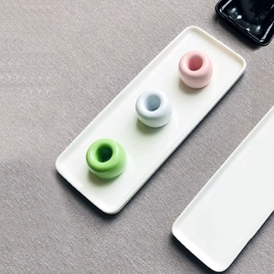 Minimalist ceramic donut toothbrush holder set with pink blue and green rings on white tray