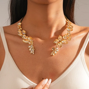 Detail of leaf-shaped champagne crystal choker on model with warm gold lighting