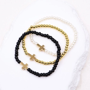 Three-piece stretch beaded bracelet set with cross charms in black, gold, and pearl white