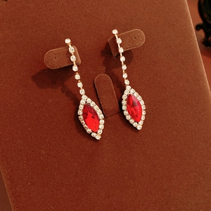 Close-up of red marquise rhinestone drop earrings with fringe on brown velvet stand