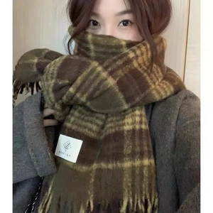 Detail of brown and yellow plaid scarf featuring soft fringe and stitched brand label