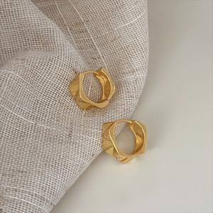 Macro view of gold-plated 925 sterling silver hoop earrings with geometric twist design