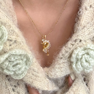 Close-up of 18k gold plated unicorn pendant necklace on a woman's beige sweater