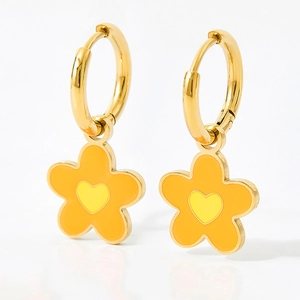 Macro detail of gold-plated hoop earrings with orange flower and yellow heart enamel charm