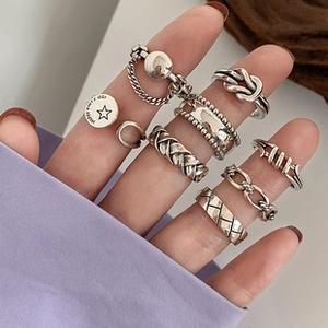 Primo piano di anelli impilabili in argento vintage con texture a nodi e catene