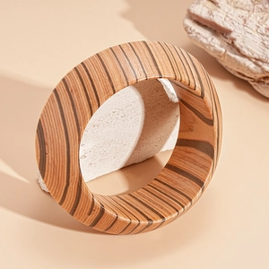 Detailed view of wide wooden grain bangle with organic brown tree ring textures on a stone