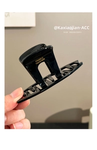 Close-up of black acrylic hair claw clip with golden France Handmade logo lettering