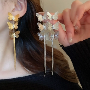 Detailed view of long butterfly tassel earrings in gold and silver with zircon accents