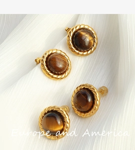 Macro shot of French luxury vintage stud earrings with tiger eye stone and gold rope border