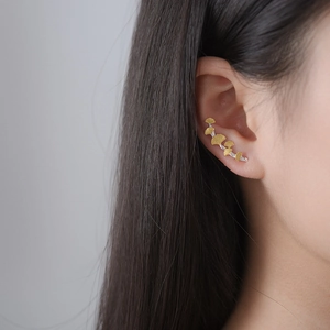 Macro detail of golden ginkgo leaf climber earring on model showing delicate textures