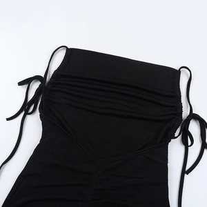 Detail of black jumpsuit with side drawstring ties and ruched fabric texture