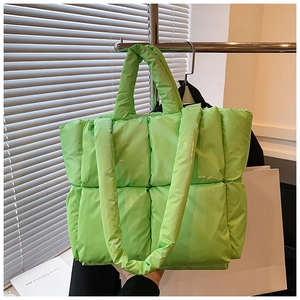 Detail view of the bright green quilted tote bag featuring a glossy nylon puffer texture