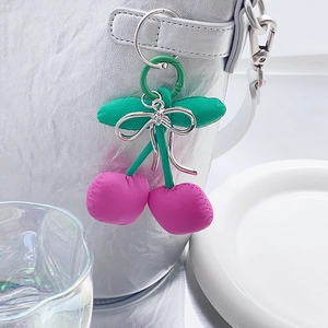 Detail of pink fabric cherry keychain with silver bow on a silver metallic bag