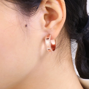 Close-up of 18k rose gold plated hoop earring with beaded edge texture on a model