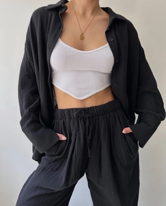 Detail of white knit crop top with V-hem under a black loose-fit long sleeve shirt