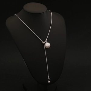 Detail of silver snake chain Y-necklace with elegant faux pearl pendant on a black bust