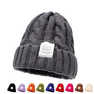 Grijze gebreide muts voor dames met kabelpatroon en decoratieve patch voor de winter