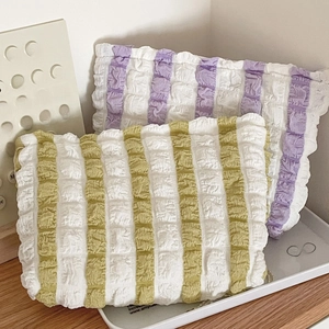 Detail view of wrinkled striped makeup bags in green and purple seersucker fabric