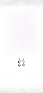 Detail of floral earrings with purple and blue teardrop crystals in a gold setting