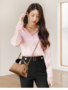 Close-up of brown leather crossbody bag with top handle worn with a pink silk shirt