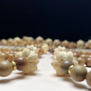 Bracelet en bois de santal vert avec lotus sculpté et perles dorées sur fond sombre