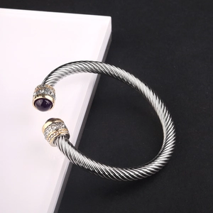 Close-up of twisted cable cuff with purple stone and gold accents on a split background