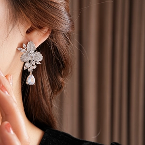 Nahaufnahme von silbernen Tropfenohrringen mit Zirkonia-Blumen- und Blattdesign am Model