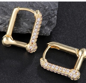 Macro view of gold rectangular hoop earrings with cubic zirconia inlay and latch closure
