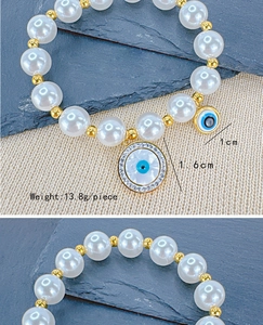 Detailed view of pearl bracelet with evil eye pendants showing 1cm and 1.6cm dimensions