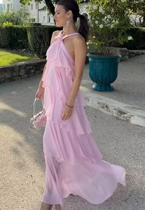 Side view of pink halter neck maxi dress with layered ruffle details and tiered hem