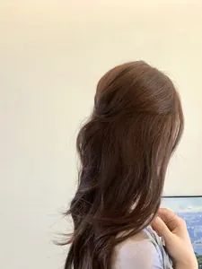 Detail view of purple matte hair claw clip styling a half-up bun on wavy brown hair