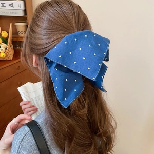 Détail d'une pince à cheveux en tissu bleu à motif cœur sur cheveux longs