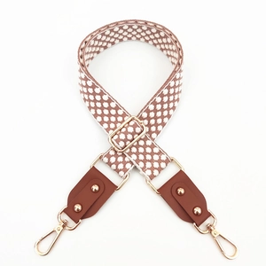 Détail de la bandoulière brodée ajustable avec bouts en cuir et boucles dorées