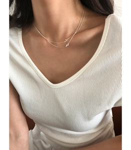 Detail of layered S925 sterling silver H letter necklace worn on a V-neck shirt