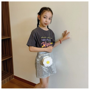 Little girl wearing round sunflower crossbody bag with silver sequin skirt and grey tee
