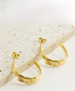 Detail of 18K gold-plated irregular geometric stud earrings on natural stone background