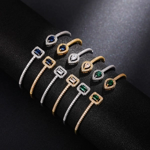 Detailed array of brass open bracelets with colorful square and teardrop zircons