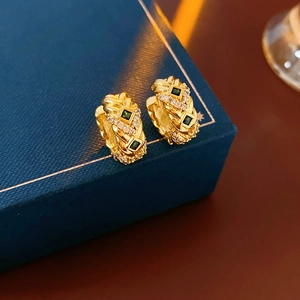 Detail of vintage gold woven earrings with green square gemstones and clear zircons in box