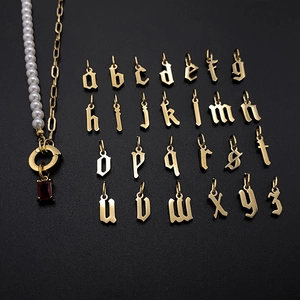 Detailed close-up of gold gothic alphabet charms with elegant pearl and link chain necklace