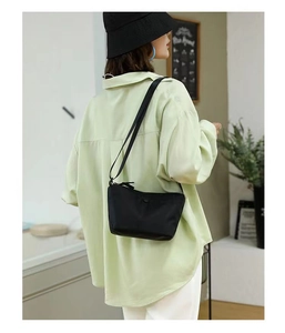 Rear view of a model wearing a black lightweight nylon crossbody dumpling bag with strap