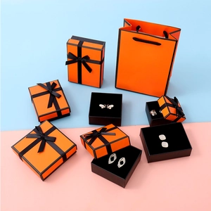Flat lay of luxury orange jewelry gift boxes and paper bag set with black ribbon detail