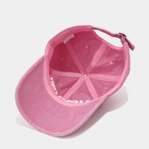 Detail view of pink cotton baseball cap interior with metal buckle and care label
