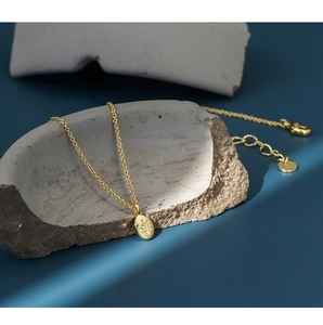 Detail of gold starburst oval pendant with zircon on a rustic grey stone texture